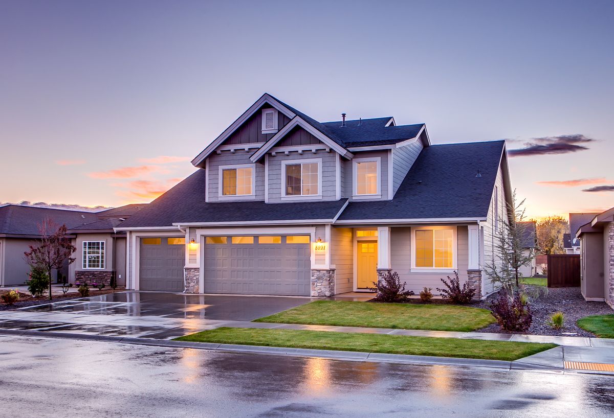 A renovated two-story home at dusk with warm lights glowing inside